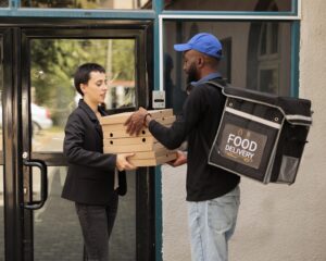 African american courier giving customer pizza order outdoors