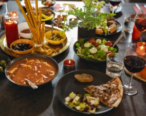 Cozy holiday table with different delicious food, beverages and candles ready for friends home party
