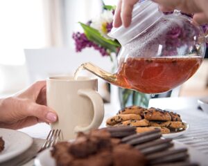 cropped shot of man pouring tea into cup during breakfast at home