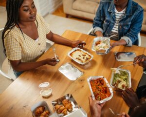 Young happy friends having fun during lunchtime at home